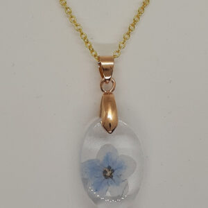 Ovaler Kettenanhänger aus klarem Epoxidharz mit großer Vergissmeinichtblüte