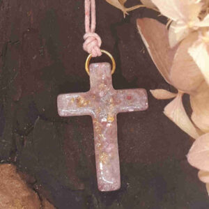 Rosafarbenes Kreuz - Kettenanhänger aus Epoxidharz mit gewachster Kordel.